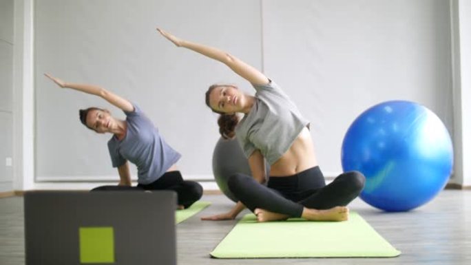 两名年轻女子在家观看在线瑜伽课程