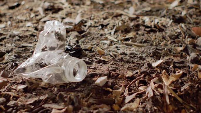 特写-塑料瓶扔在另一个留在土壤上的瓶子旁边。环境问题、土壤污染和垃圾填埋概念。