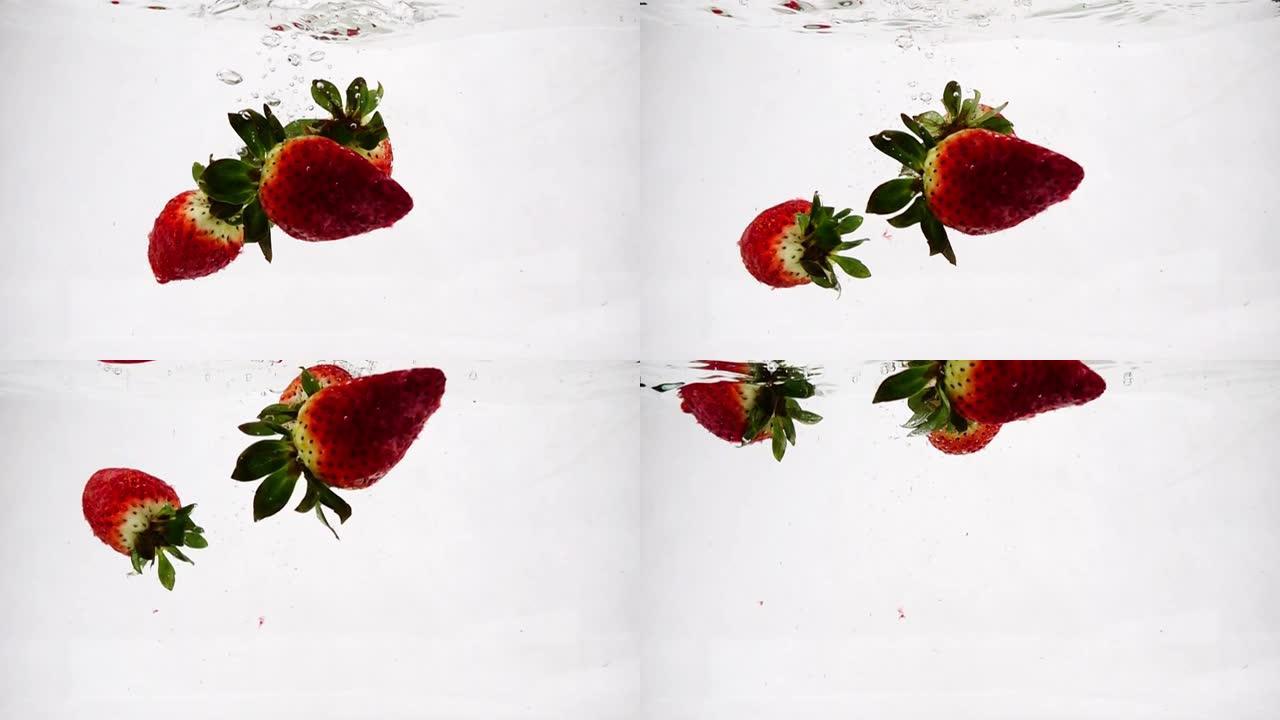 草莓以慢动作飞溅和气泡落入水中。