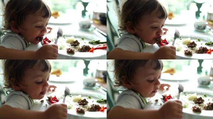 吃饭时，小男孩把食物吐进盘子里。儿童吐出食物