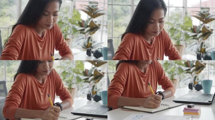 亚洲创意女性在家工作时在笔记本上写下规划大项目的想法。
