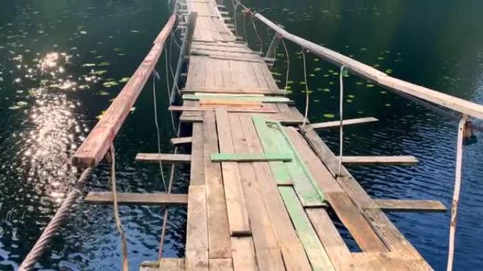 在湖边的绿色森林中悬挂古老的木桥，一缕阳光反射在水波纹上