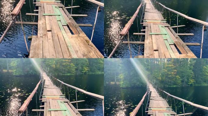在湖边的绿色森林中悬挂古老的木桥，一缕阳光反射在水波纹上