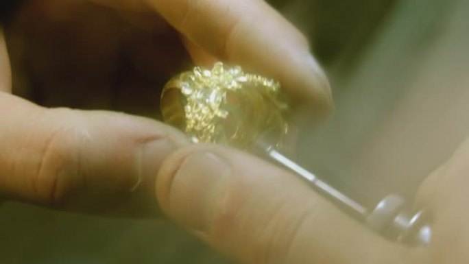 用抛光机和圆形旋转砂纸或旋转工具制作黄色金戒指的人的手。特写镜头。金匠用抛光机抛光银或金戒指
