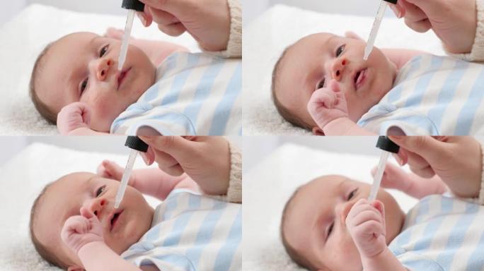 母亲从吸管给刚出生的小儿子服用维生素d和K的特写镜头。婴儿和新生儿疫苗接种和医疗保健的概念。有小孩的