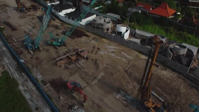 一架无人机飞越高高的建筑起重机的视频，在地面上建造了一座新建筑
