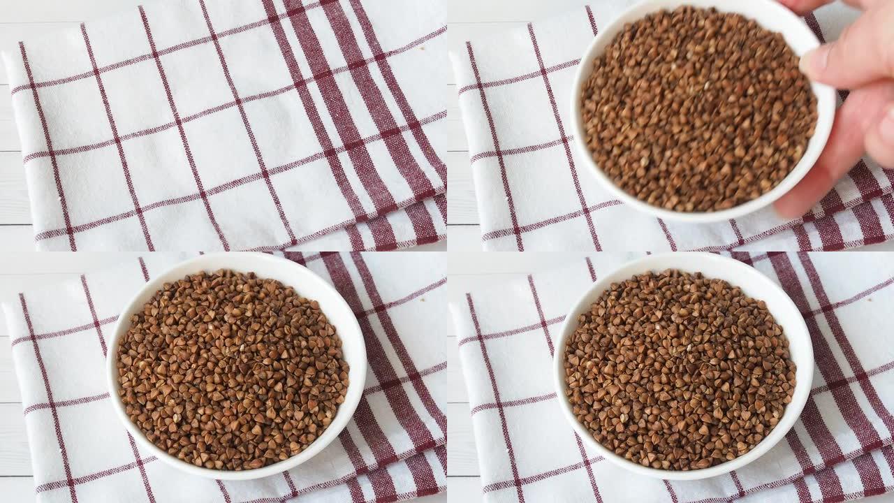 生荞麦粥放在桌子上的陶瓷盘里。特写