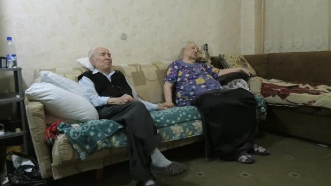 一个年老的男人和女人坐在沙发上。