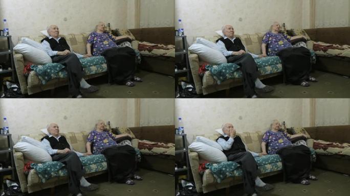 一个年老的男人和女人坐在沙发上。