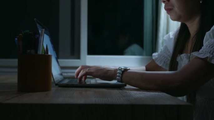 女人手上的特写镜头是在电脑笔记本电脑上打字，晚上在家工作，检疫是从Covid 19大流行冠状病毒新的
