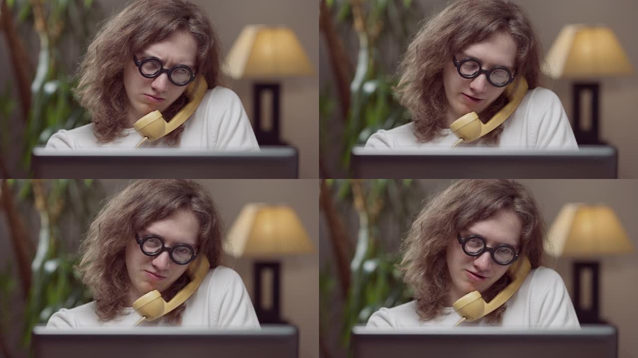 智能集中20世纪80年代男子在黄色老式电话上聊天的肖像，室内坐着复古笔记本电脑。天才高加索年轻人在家