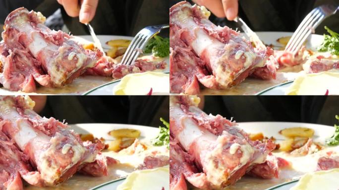 男性用刀叉切割手，在餐厅吃新鲜烹制的美味猪脚