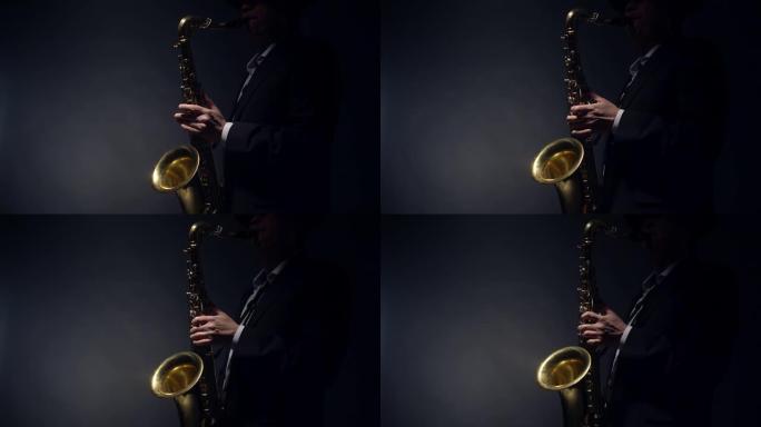 萨克斯管演奏者通过吹入吹嘴并用手指在工作室中以灰色背景，纵断面视图按下襟翼来演奏闪亮的金色萨克斯管。