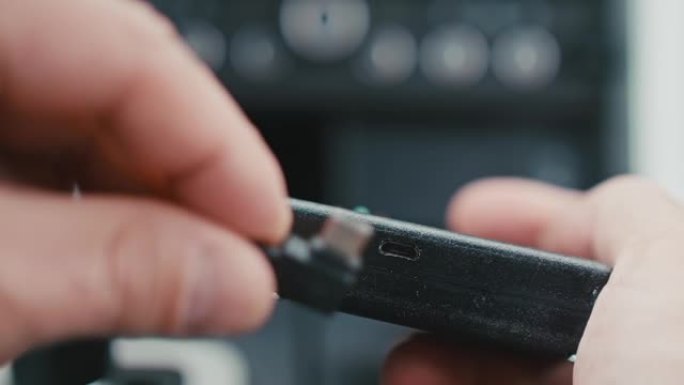 带迷你USB端口的黑色电子设备的聚焦视图。将迷你USB插入端口的人手特写。