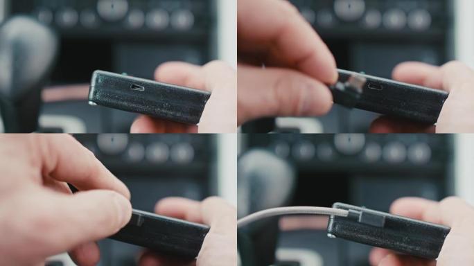 带迷你USB端口的黑色电子设备的聚焦视图。将迷你USB插入端口的人手特写。