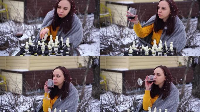 年轻女子在院子里下棋。冬季穿着灰色格子的女性坐在街上玩棋盘游戏