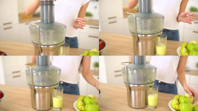 女人在榨汁机上制作苹果汁，然后在厨房的家中新鲜饮用。榨汁和健康饮食快乐的女人制作绿色蔬菜和果汁