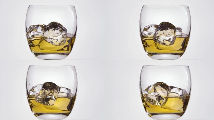 带有威士忌和冰块的玻璃杯在白色背景上顺时针缓慢旋转。