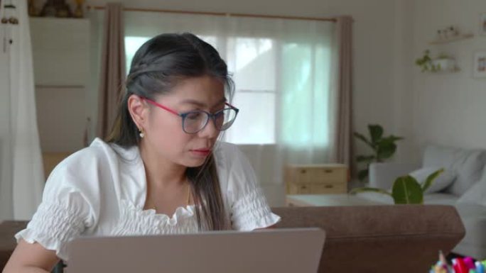 年轻的亚洲女性在电脑笔记本电脑上打字，并在检疫期间在家工作，冠状病毒Covid 19大流行是新的正常