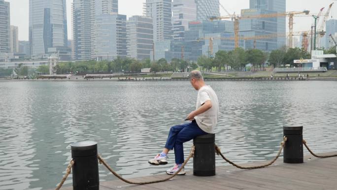 孤独的老人湖边玩手机