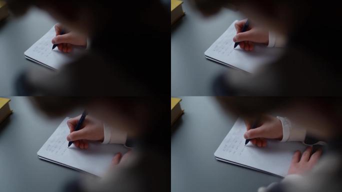 小学生男孩在笔记本上写的特写手坐在家里的桌子上解决数学方程式。