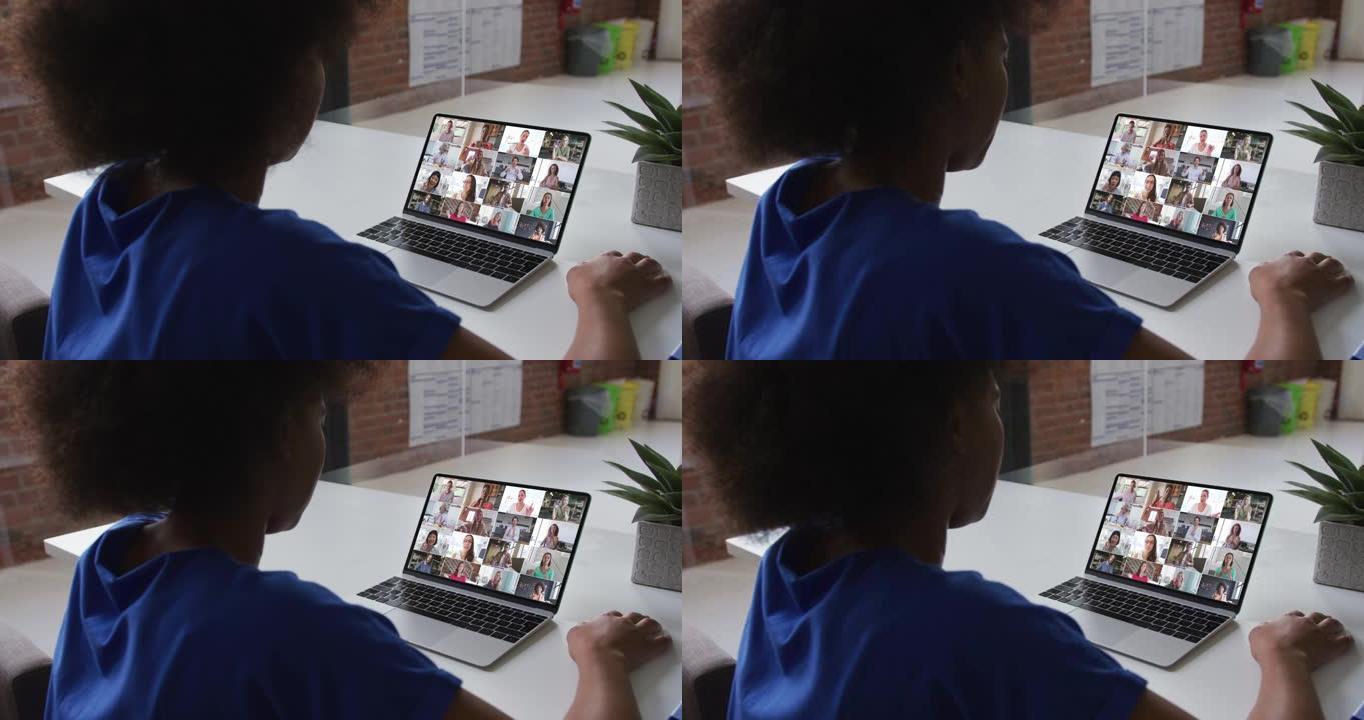 非裔美国妇女在办公室与同事在笔记本电脑上进行视频会议的后视图