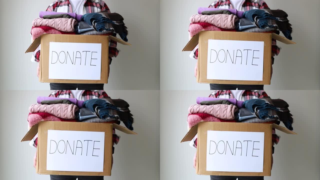 男子拿着一个捐赠衣服的盒子。捐赠理念。