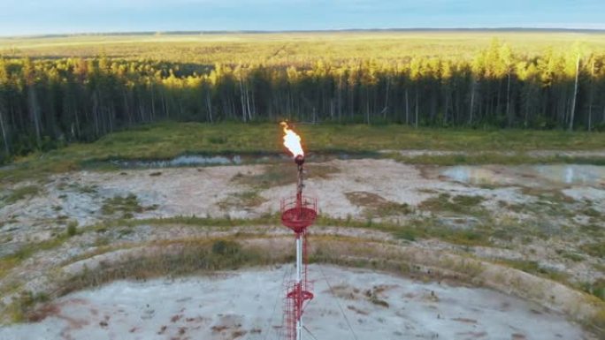 在西伯利亚沼泽的一个油田，一架无人驾驶飞机绕着燃烧的火炬飞行。火炬燃烧掉多余的伴生石油气。无人机航拍