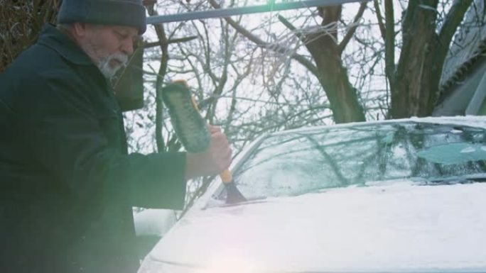 留着胡须的老人清洁电动汽车挡风玻璃