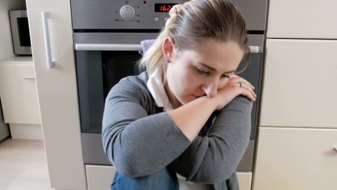 4k特写平移视频悲伤疲惫的年轻女子坐在厨房地板上哭泣