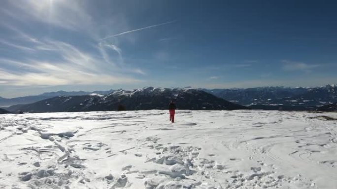 奥地利Bad Kleinkirchheim的一名穿着冬装的妇女在高山山顶上的粉末雪上奔跑。她面前有一