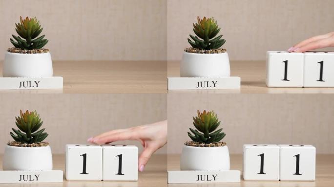 木制日历对7月11日来说是一个重要的事件，女人的手在日历上设置日期。夏季。