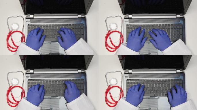 笔记本电脑的俯视图和医生的手，乳胶手套在键盘上打字，听诊器在aldo