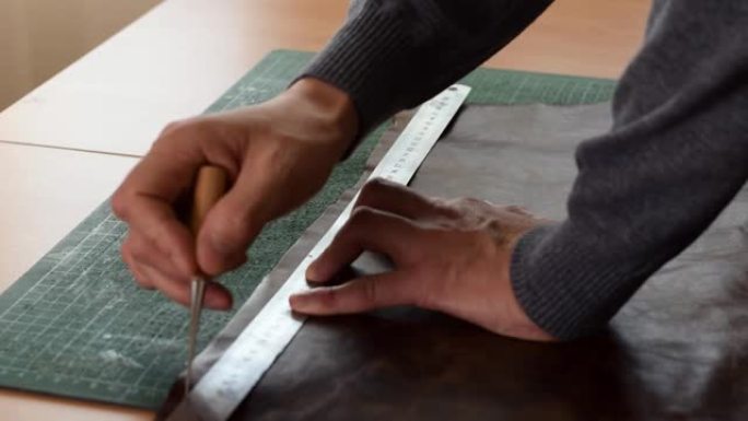 坦纳 (Tanner) 用尺子和锥子在棕色皮革上做标记。手工皮革制造商。爱好概念
