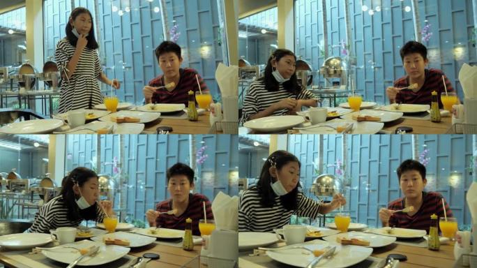 快乐的亚洲儿童在度假期间与家人一起在酒店附近的自助餐厅一起吃早餐，生活方式理念。