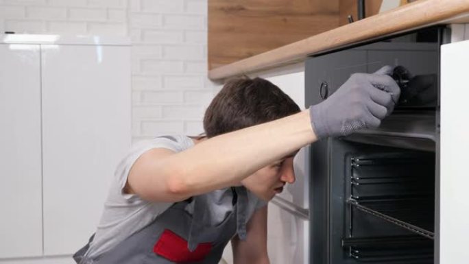 工人在宽敞的厨房里转动杠杆检查破损的烤箱