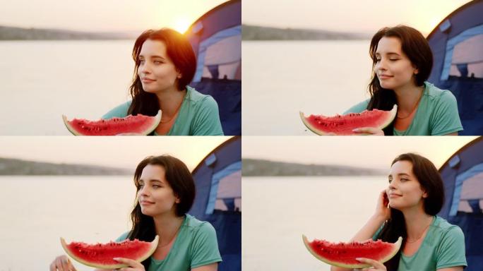 在日落的野餐特写镜头上，美丽的女人带着一大块西瓜享受着大自然的时光。在阿里·阿列克谢拍摄