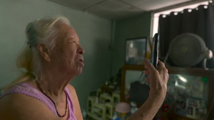 在卧室里使用智能手机vdo呼叫与家人交谈的快乐亚洲高级女性的电影拍摄。