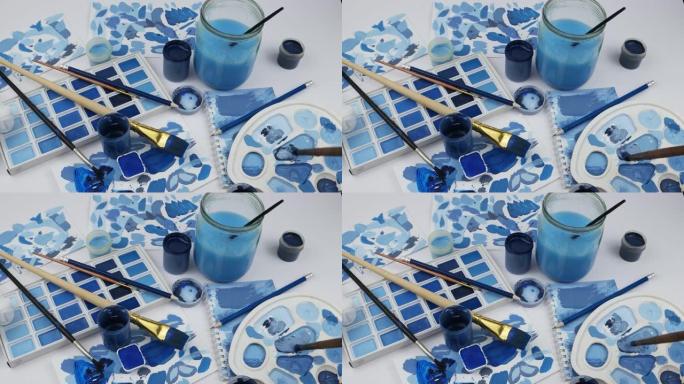 蓝色水粉与艺术家调色板中的白色刷子混合在一起