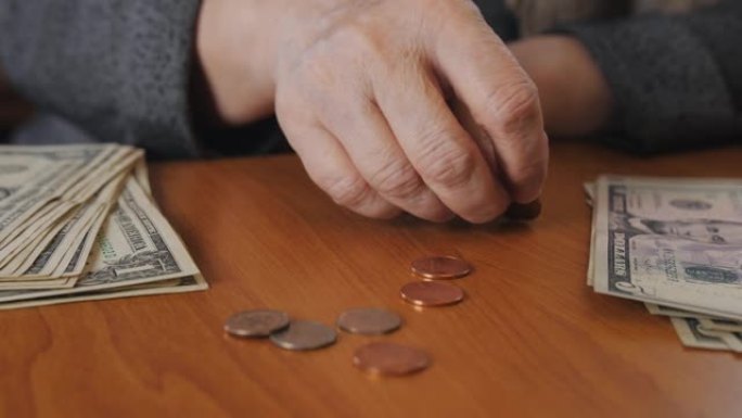 一位老年妇女指望金属硬币以维持生计。老年贫困的概念。
