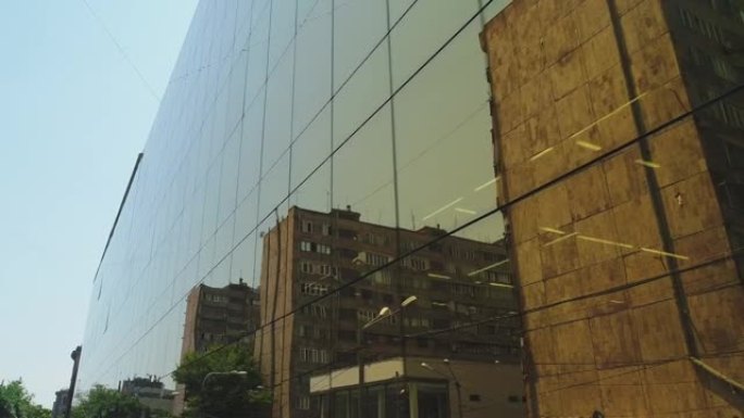 商业区大楼或购物中心的4k室外景观，白天有壁镜窗户。阳光。镜像墙壁上的城市，汽车和塔楼的反射。无人机