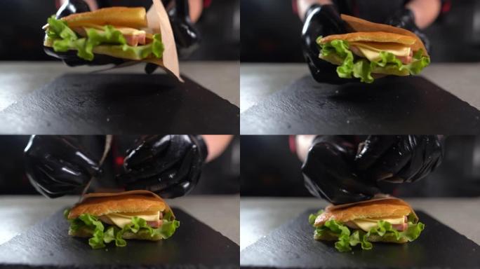 在厨房用火鸡火腿制作focaccia的过程。厨师手的特写镜头拿一个三明治，装在工艺袋里。