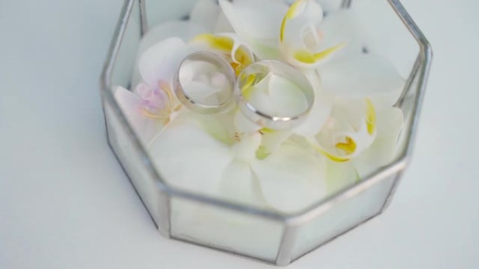梳妆台上的婚礼配件: 白色牡丹新娘花束，玻璃盒中的结婚戒指，金鞋。婚礼上午准备