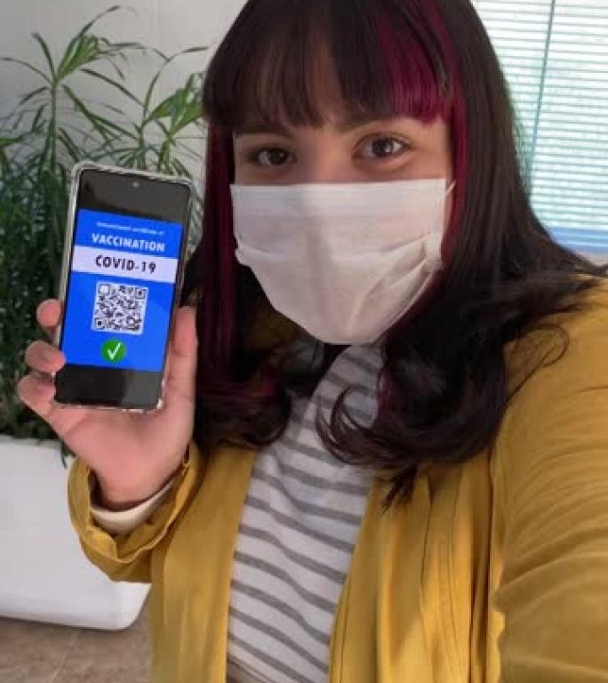十几岁的女孩在智能手机上展示新型冠状病毒肺炎的数字疫苗护照。新常态。垂直视频。