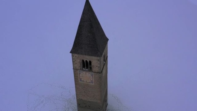 无人驾驶飞机鸟瞰图村庄的旧钟楼从Resia湖中升起