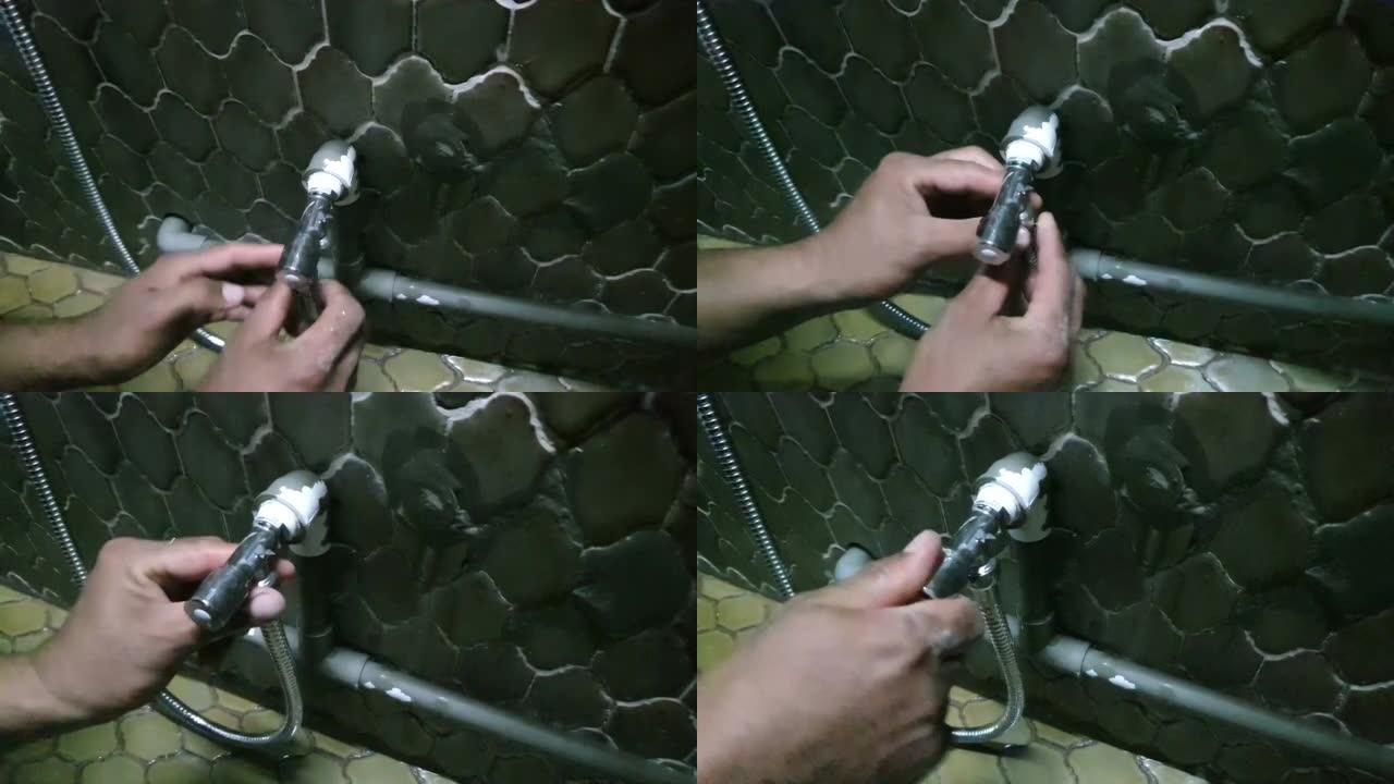 修理工使用可调扳手将马桶软管连接到墙上的截止阀并拧紧