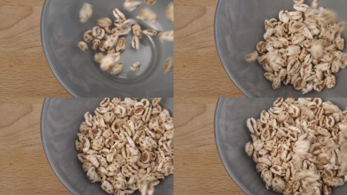 未煮熟的谷物膨化小麦掉落并装满灰色碗