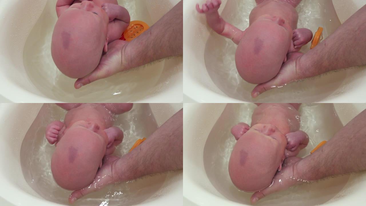父亲抱着婴儿洗澡和洗衣服，1个月大的婴儿在家浴室的塑料浴缸里。