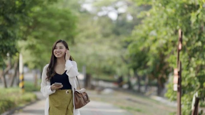 在城市街道上使用智能手机的亚洲妇女