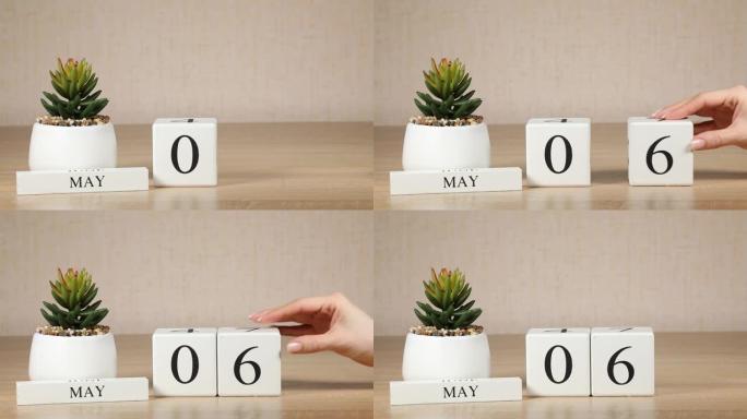 木制日历对5月06日来说是一个重要的事件，女人的手在日历上设置日期。春季。